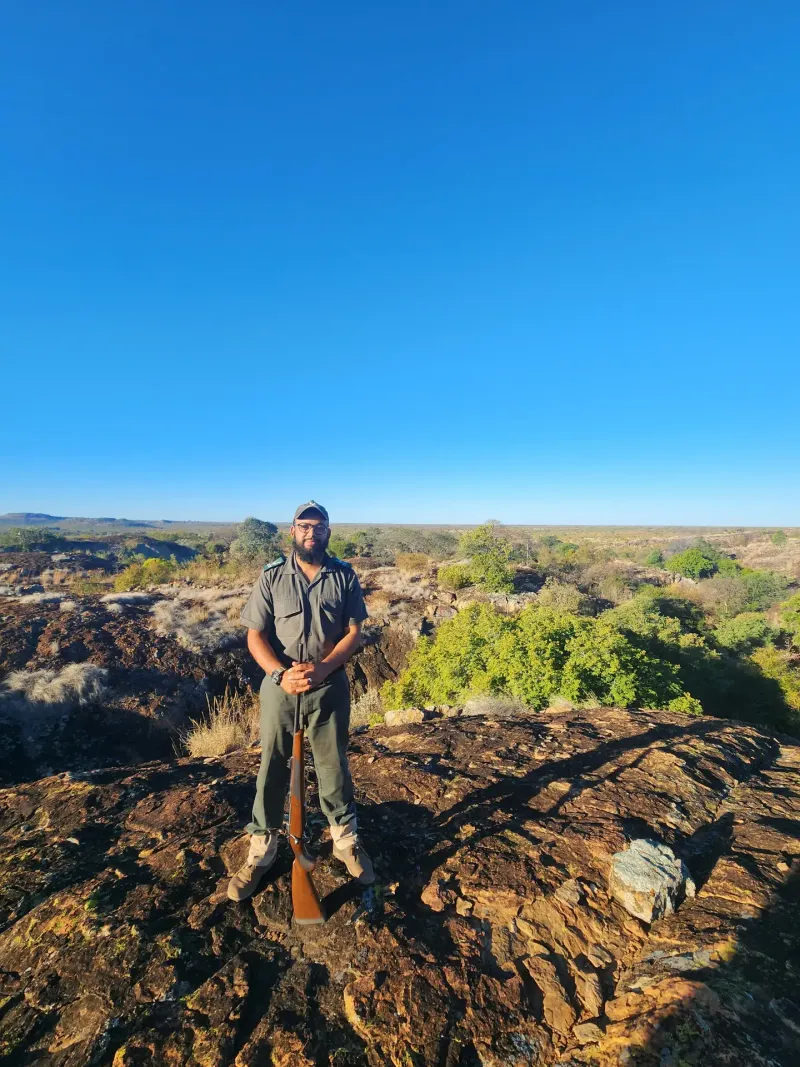 Safari guide standing on rocky mountain ridge