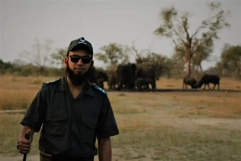 Safari guide posing with elephant herd behind